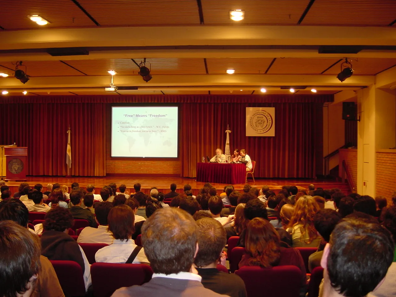 Jon “maddog” Hall no palco diante do público durante uma palestra na CaFeCONF 2005